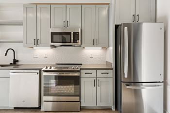 A modern kitchen with a refrigerator, oven, and microwave.